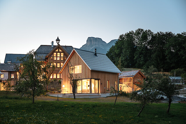Schmiedgut - Abendlich erleuchtetes Design-Ferienhaus Wald & Wiese und das historische Haupthaus