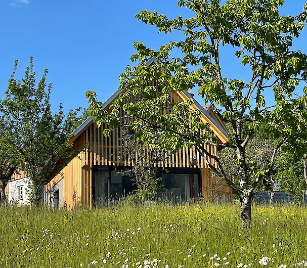 Schmiedgut - Zirbenwipfel - Hausansicht in der Sommersonne vom Obstgarten aus gesehen